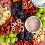 Overhead view of a charcuterie board with jelly, pate, blackberries, and assorted meats and cheese.