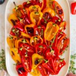 Overhead view of a platter of roasted mini sweet peppers with garlic and thyme.