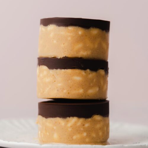 A stack of three crunchy peanut butter cups on a plate.