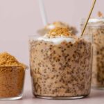 A glass of brown sugar shaken espresso overnight oats topped with yogurt, some chopped nuts, and brown sugar.