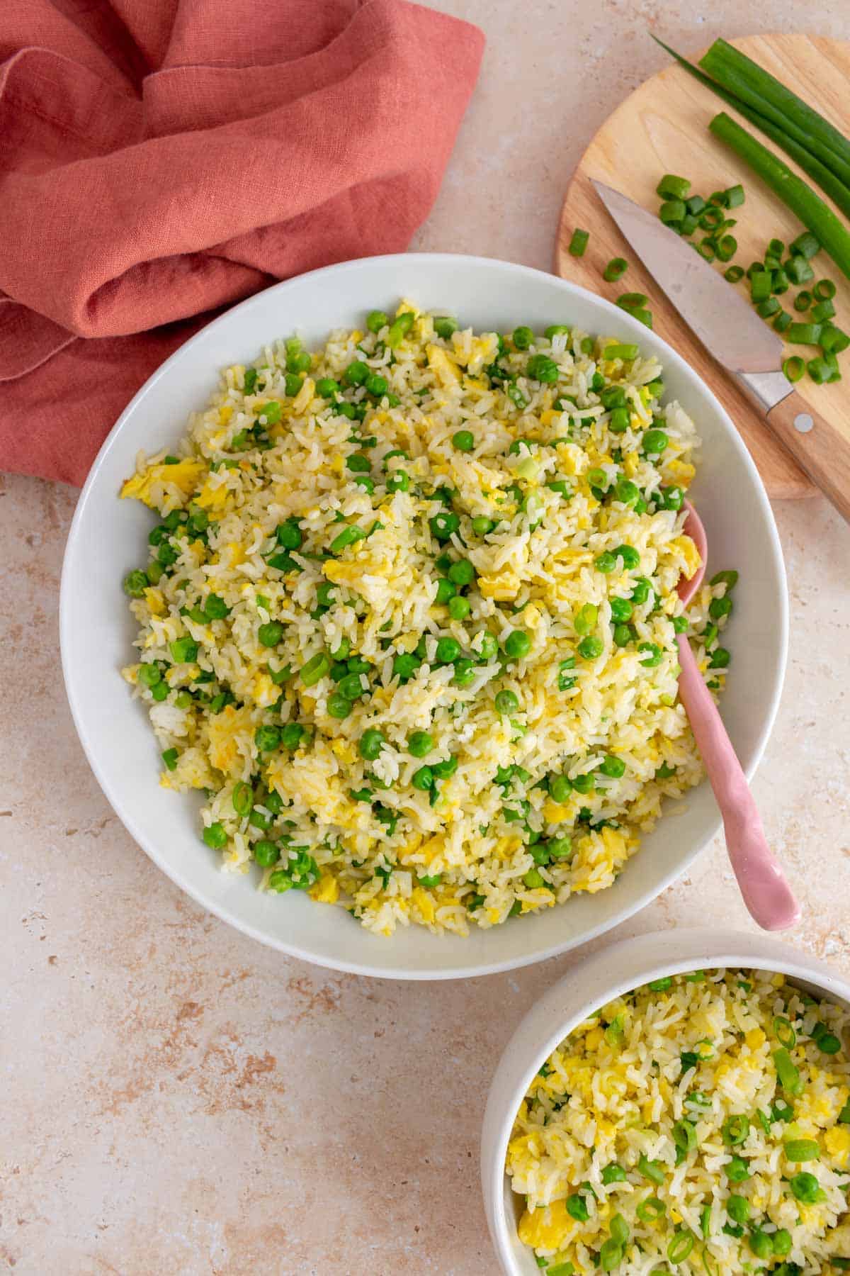 Overhead view of a large bowl of egg fried rice with a spoon and a small bowl of rice on the side.