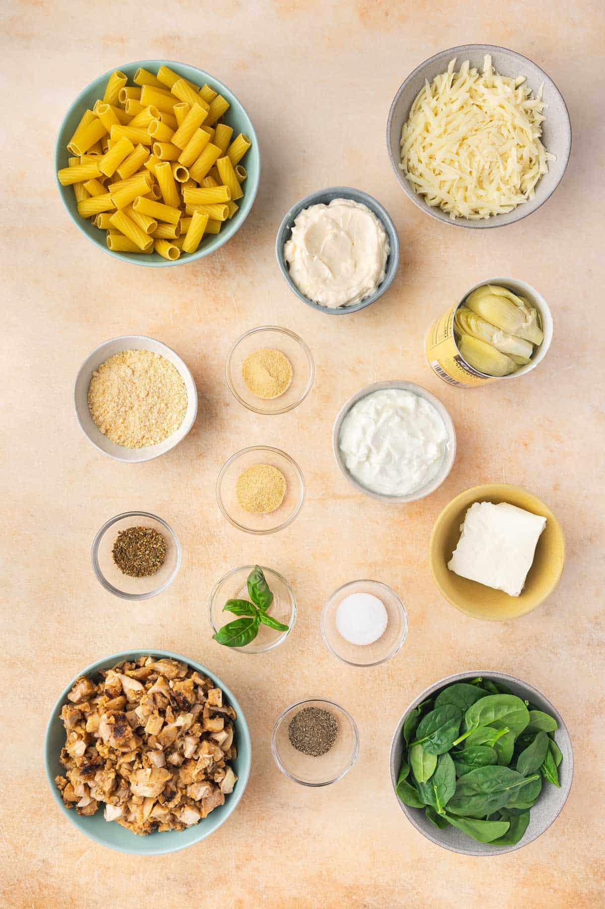 Ingredients needed to make a spinach and artichoke pasta bake.