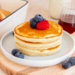 A plate with a stack of fluffy pancakes with protein powder topped with berries.