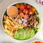 Overhead view of a burger bowl with special sauce drizzled over top.