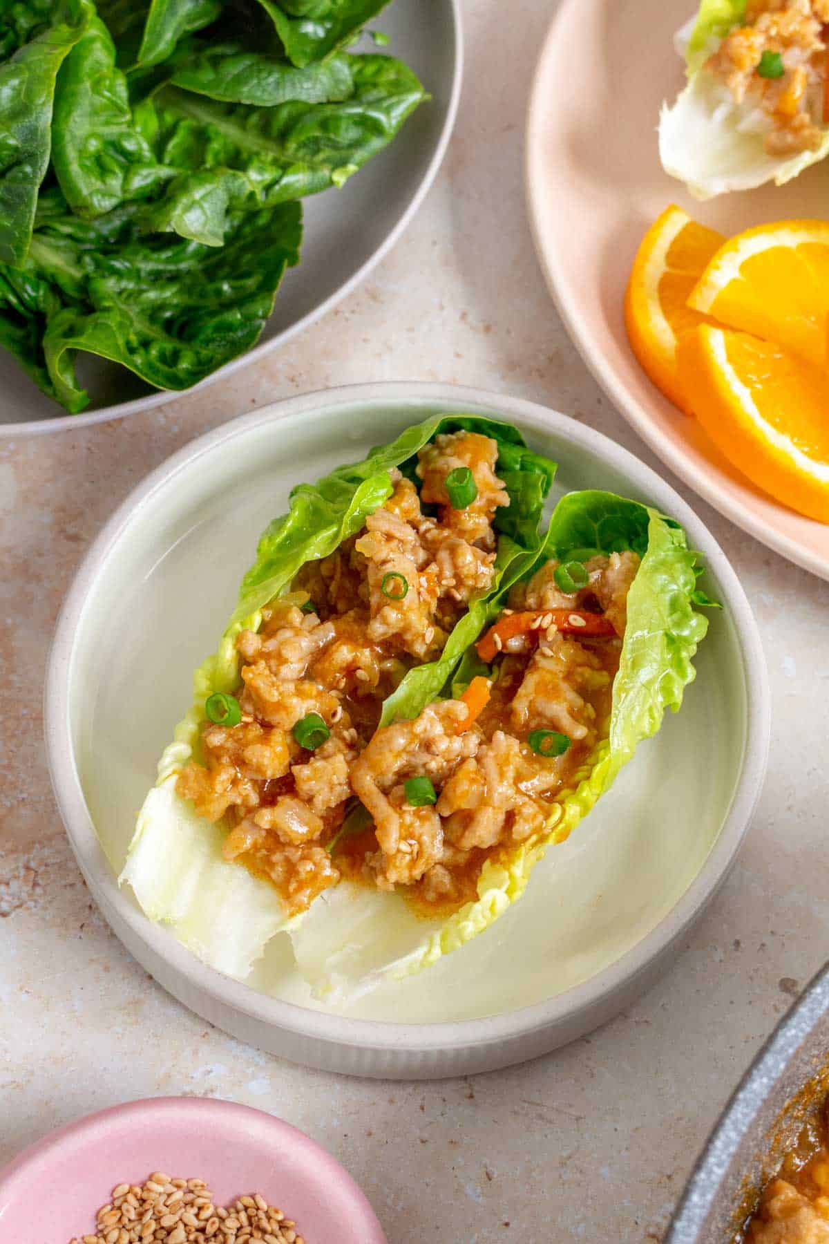 A small plate with two spicy orange chicken lettuce wraps.