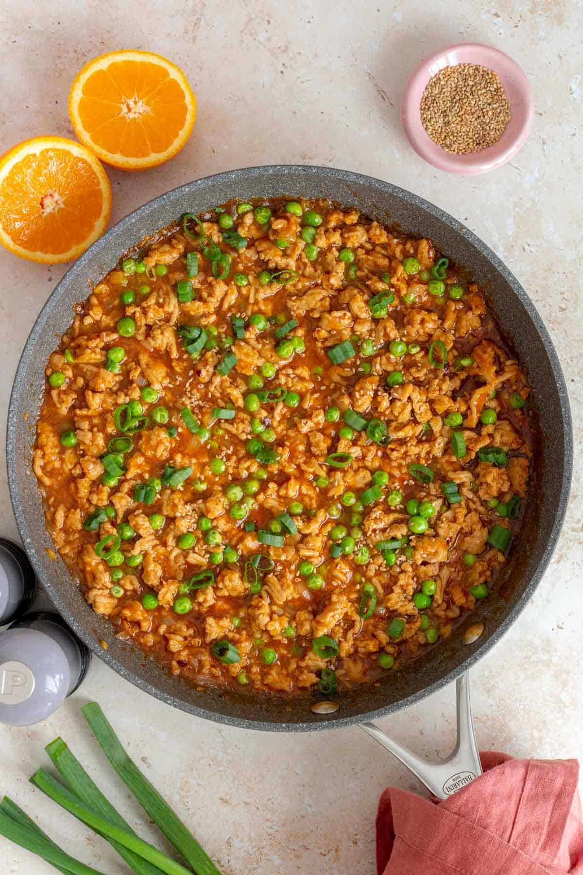 A skillet of volcano chicken topped with sesame seeds and green onions.
