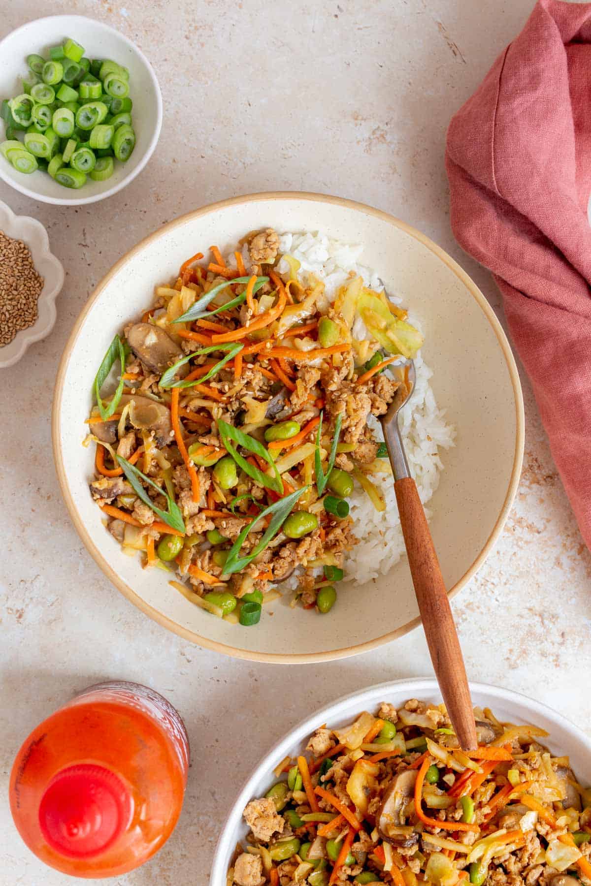 A bowl of egg roll in a bowl with ground turkey and extra veggies over rice with a fork.