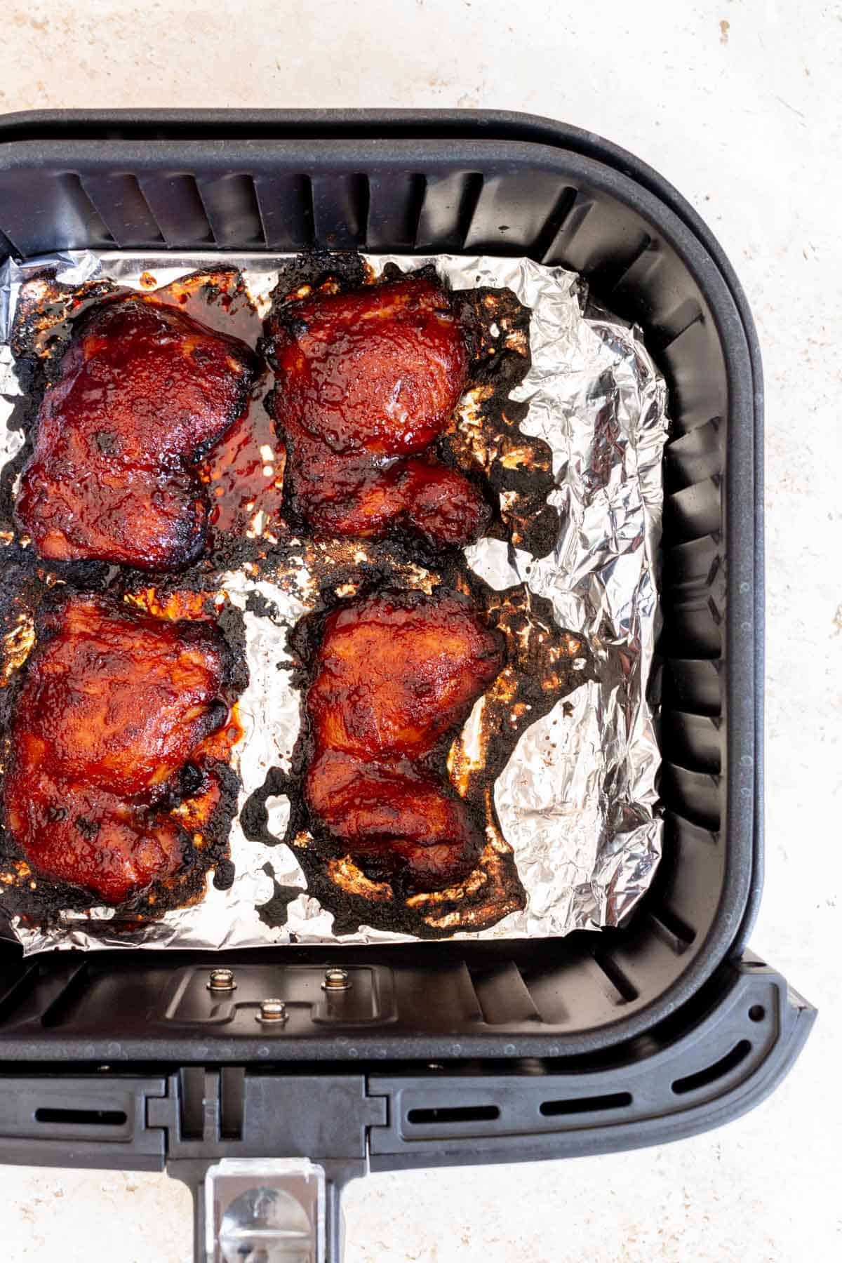 Close up view of char siu chicken in an air fryer basket.