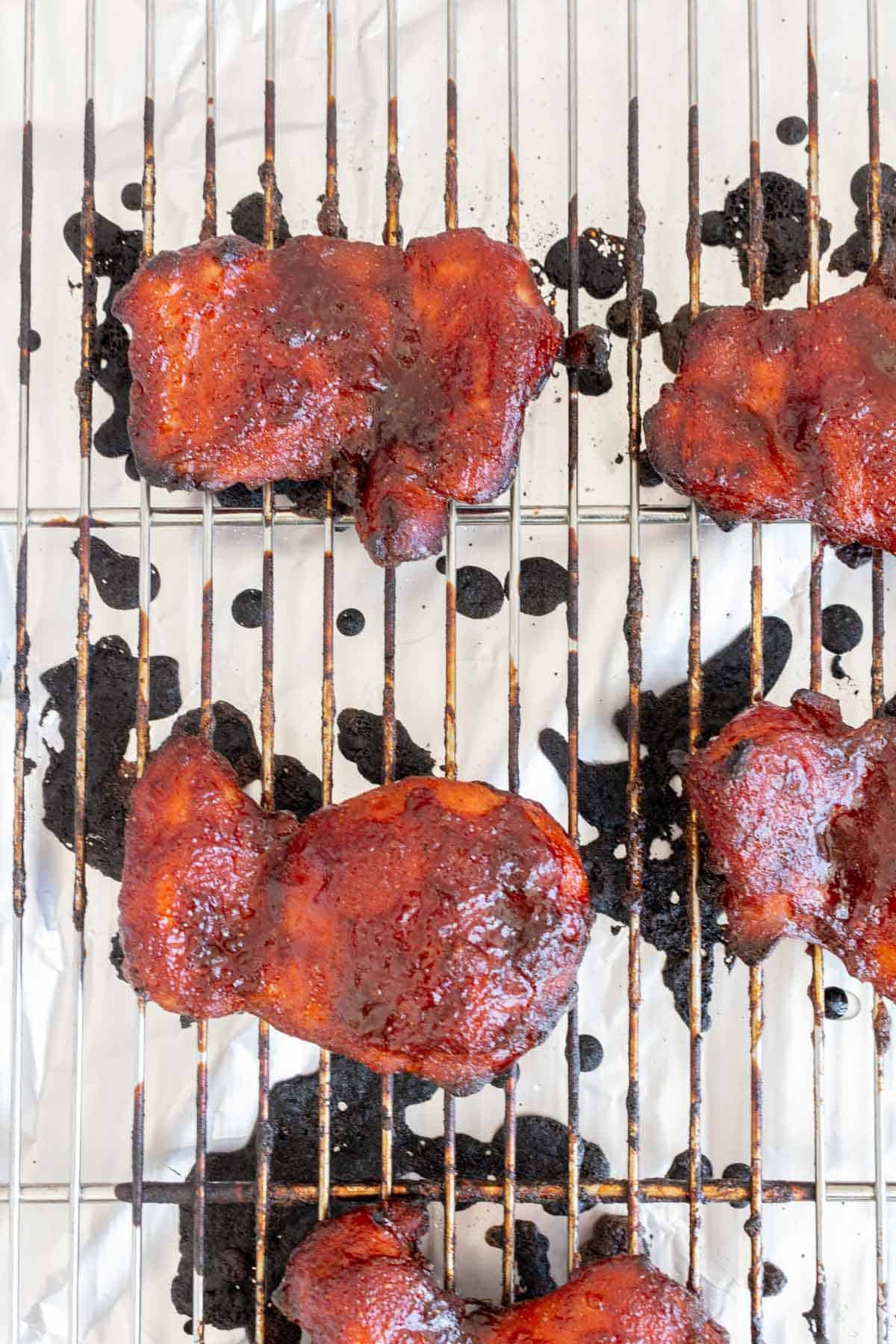 A close up view of baked char siu chicken thighs on a rack.