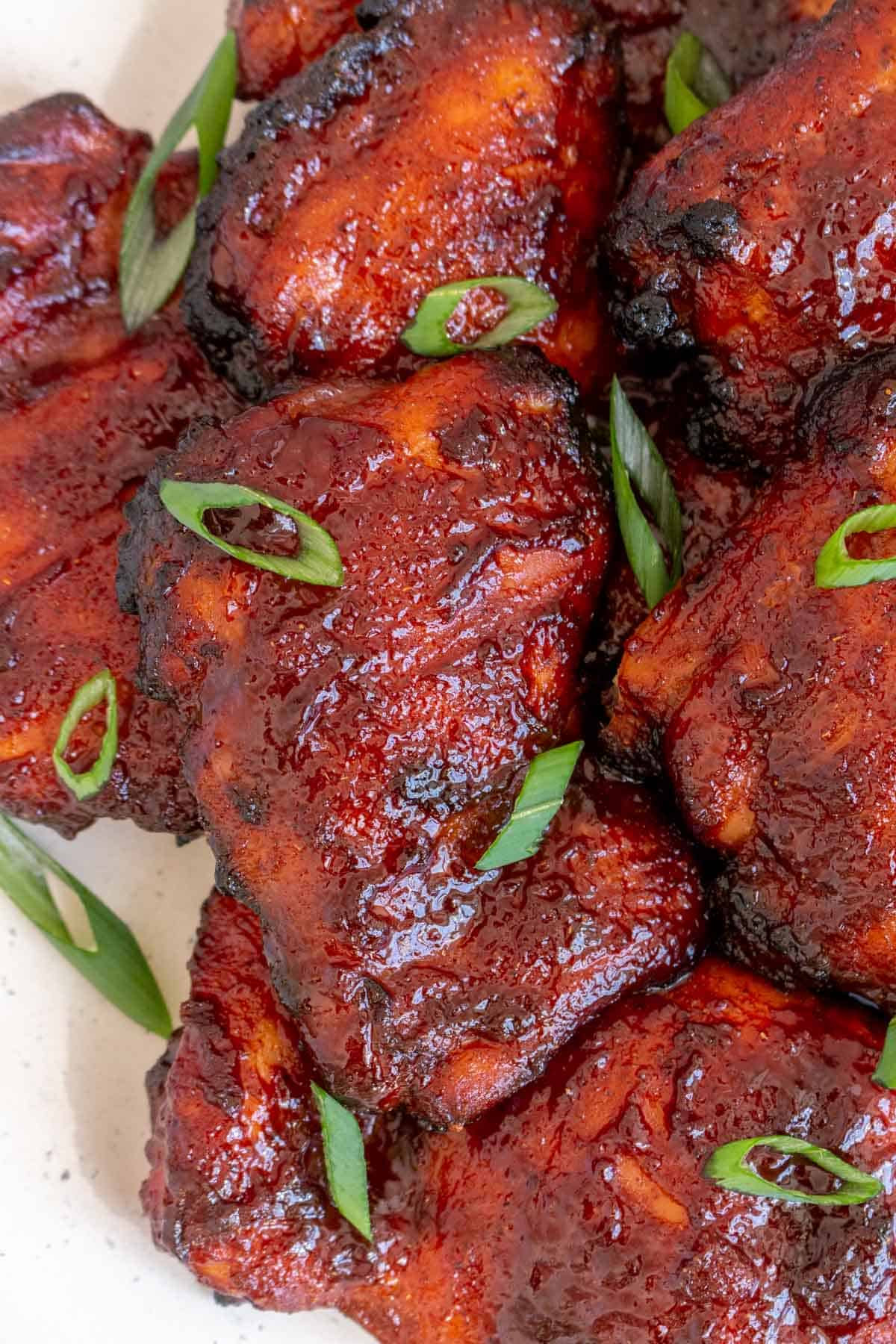 A close up view of char siu chicken on a plate garnished with green onions.