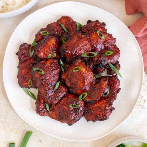 Overhead view of a platter with multiple char siu chicken topped with green onions.