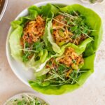 A plate with three firecracker ground chicken lettuce wraps.