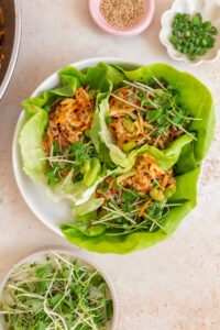 A plate with three firecracker ground chicken lettuce wraps.