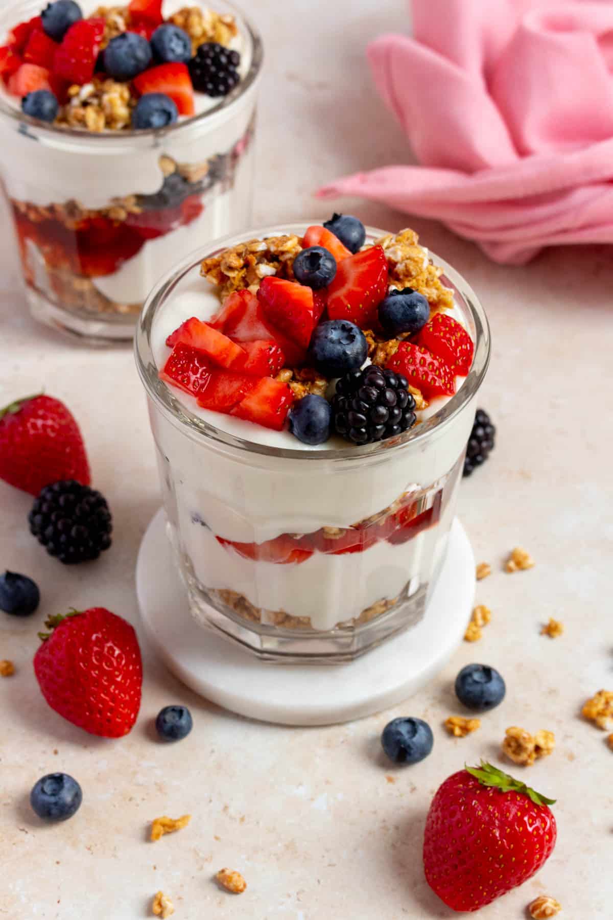 A jar of cottage cheese parfait on a white coaster with another jar in the background.