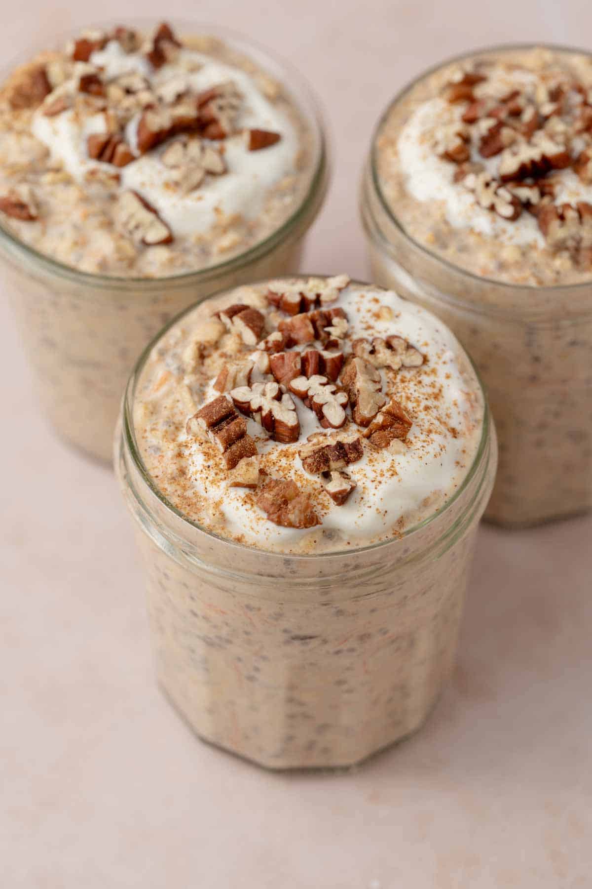 Three jars of carrot cake overnight oats with one pulled in front.