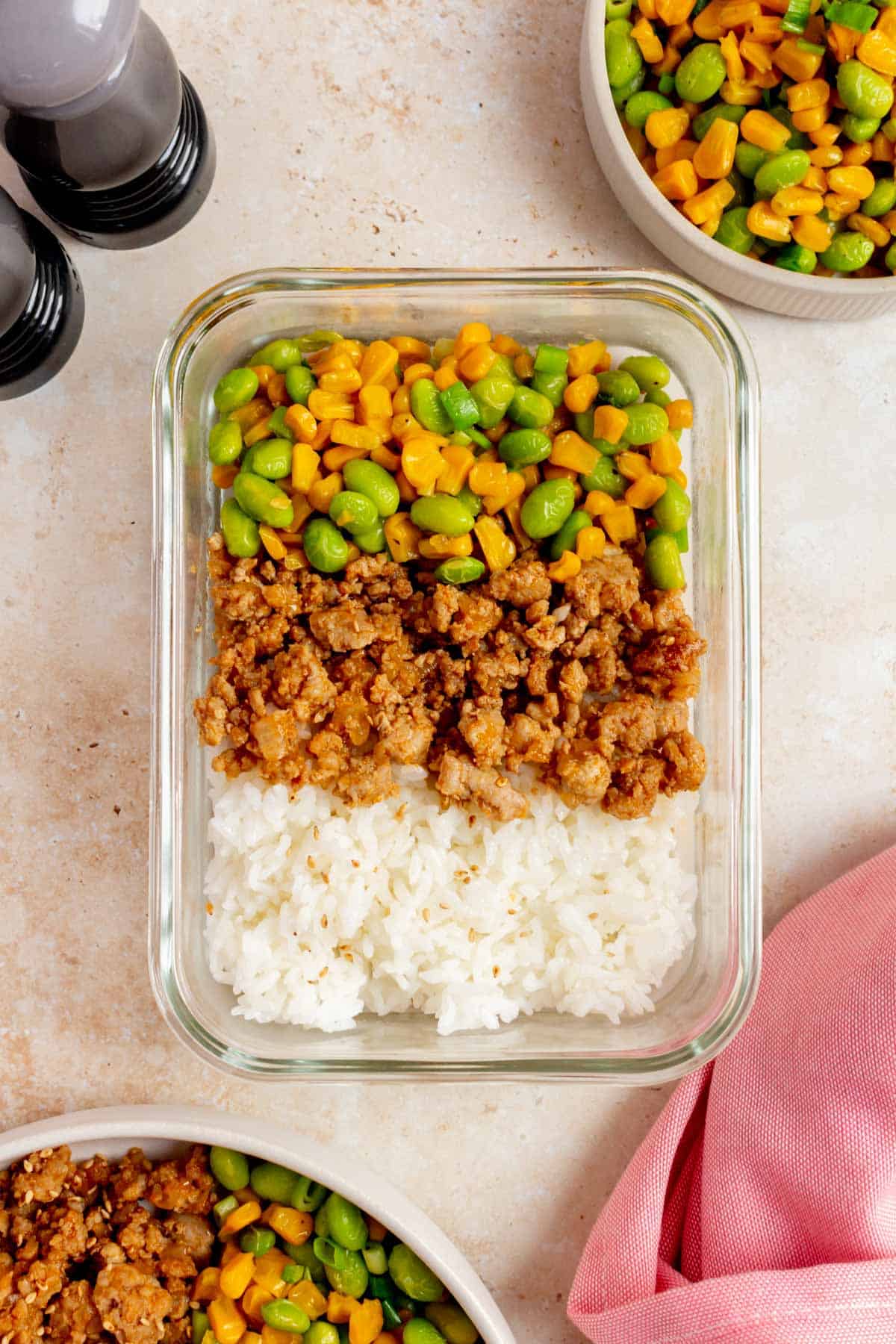 A meal prep container of hot honey ground pork with corn, edamame, and rice.