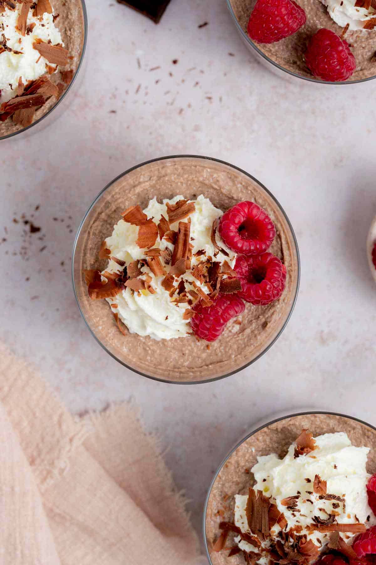 Overhead view of a jar of blended chocolate overnight oats topped with whipped cream, shaved chocolate, and raspberries.