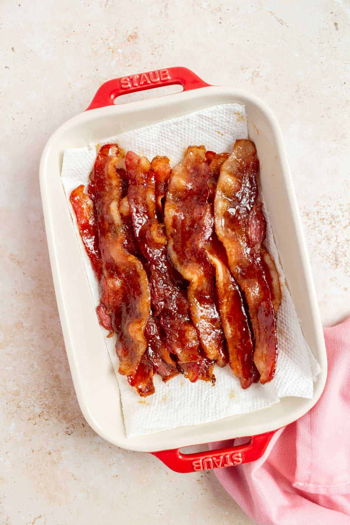 A paper towel on a dish with brown sugar bacon on top.