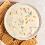 Overhead view of a bowl of funfetti greek yogurt dip with crackers beside it.