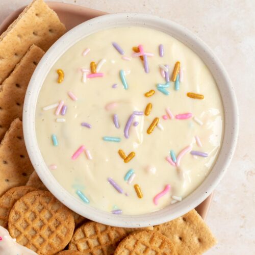 Overhead view of a bowl of funfetti greek yogurt dip with crackers beside it.