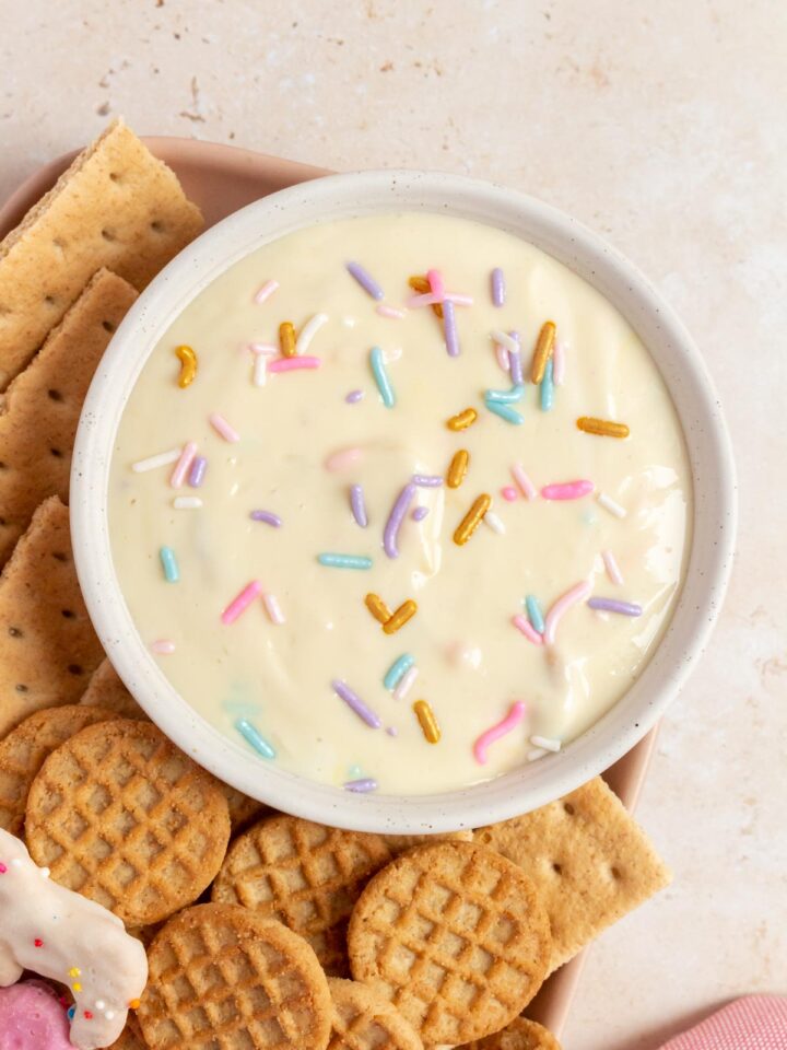 Overhead view of a bowl of funfetti greek yogurt dip with crackers beside it.
