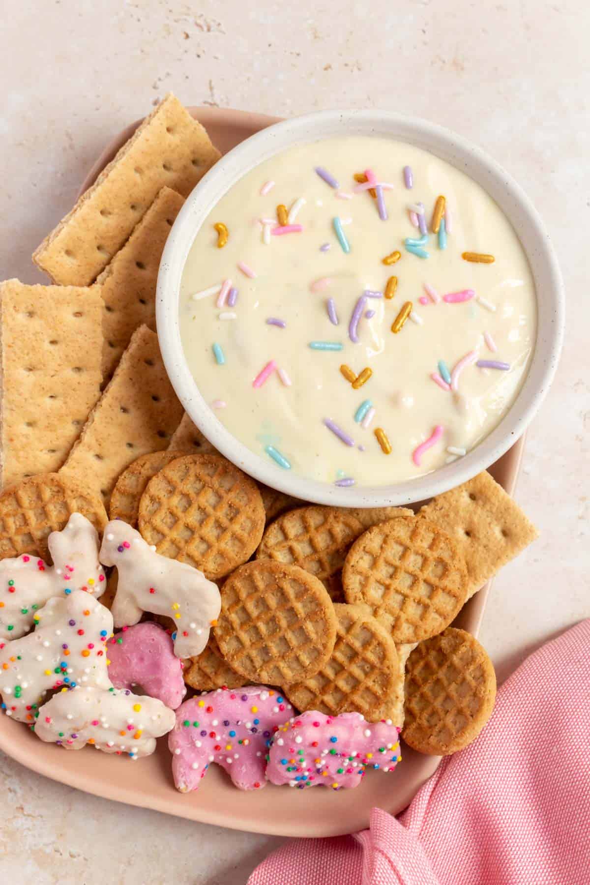 Overhead view of a platter of cookies with a bowl of funfetti greek yogurt dip.
