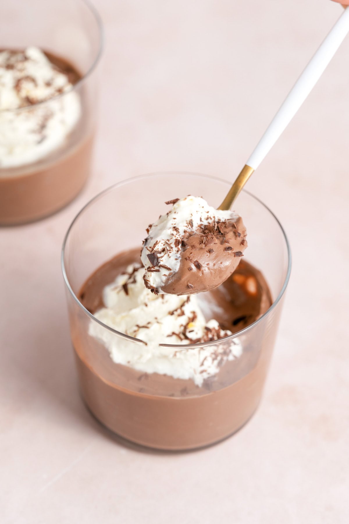 A spoonful of chocolate tofu pudding with whipped cream lifted from the jar.