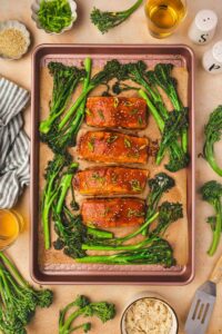 Overhead view of sheet pan gochujang salmon with broccolini topped with sesame seeds and green onion garnish.