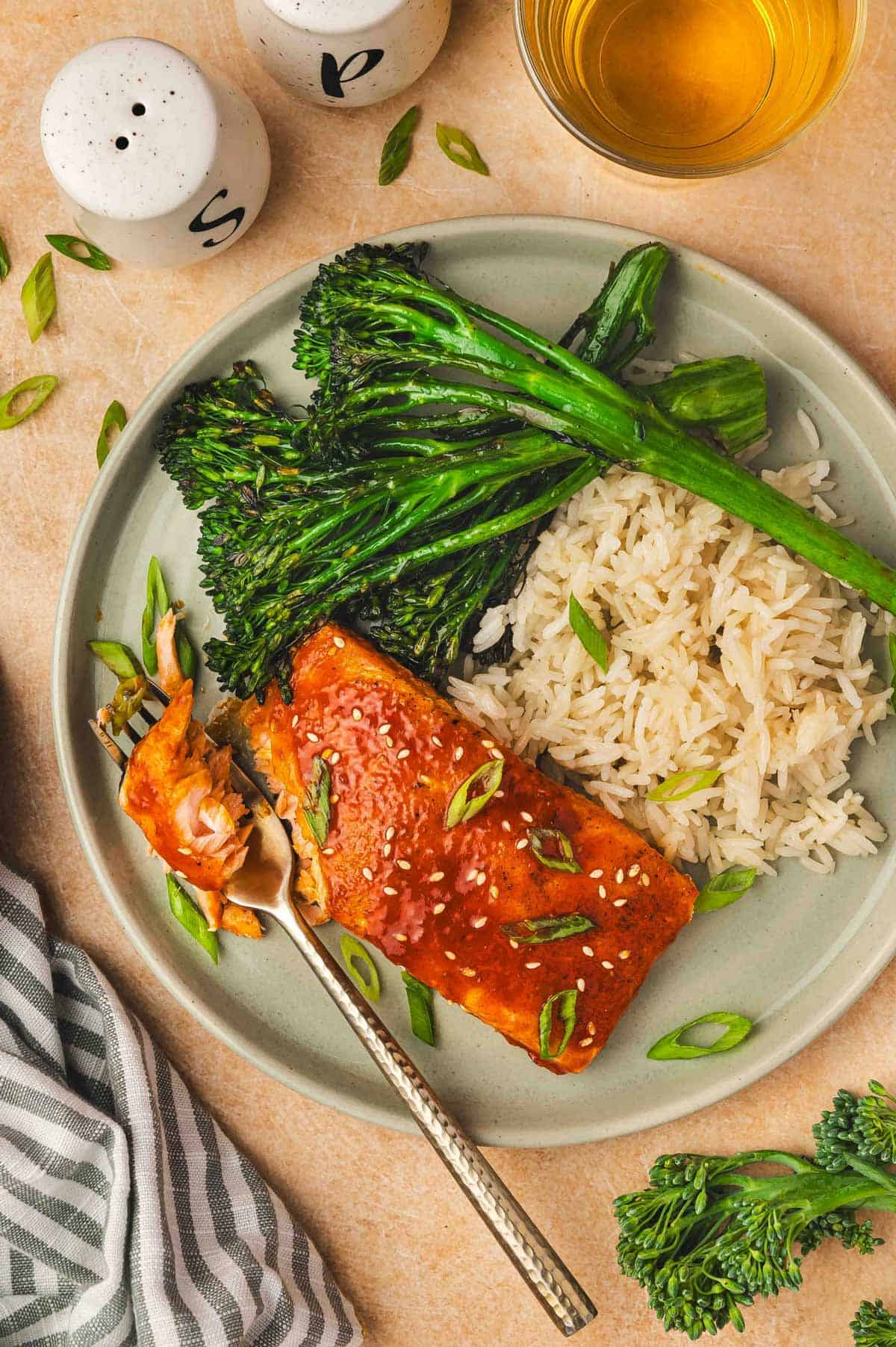 An overhead view of a plate with gochujang salmon with broccolini and rice with a fork.