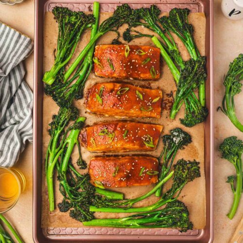 Overhead view of sheet pan gochujang salmon with broccolini topped with sesame seeds and green onion garnish.