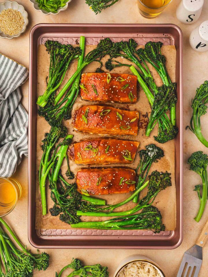 Overhead view of sheet pan gochujang salmon with broccolini topped with sesame seeds and green onion garnish.