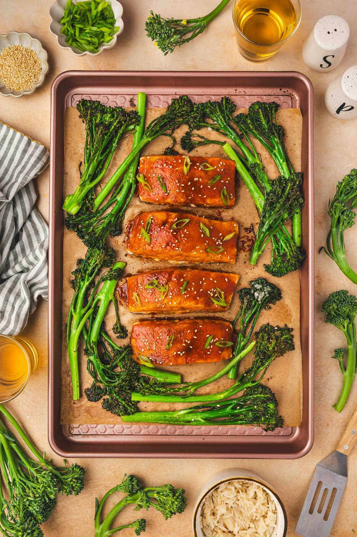Overhead view of sheet pan gochujang salmon with broccolini topped with sesame seeds and green onion garnish.