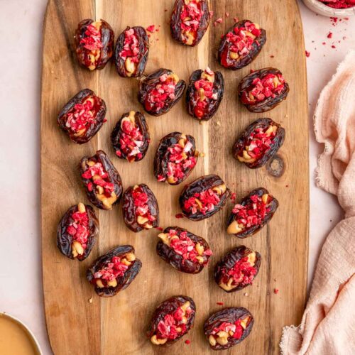 An overhead view of a wooden serving board with peanut butter and jelly stuffed dates.
