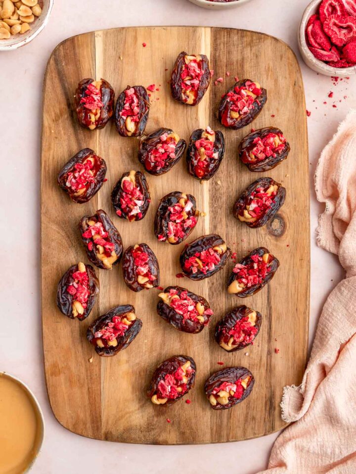 An overhead view of a wooden serving board with peanut butter and jelly stuffed dates.