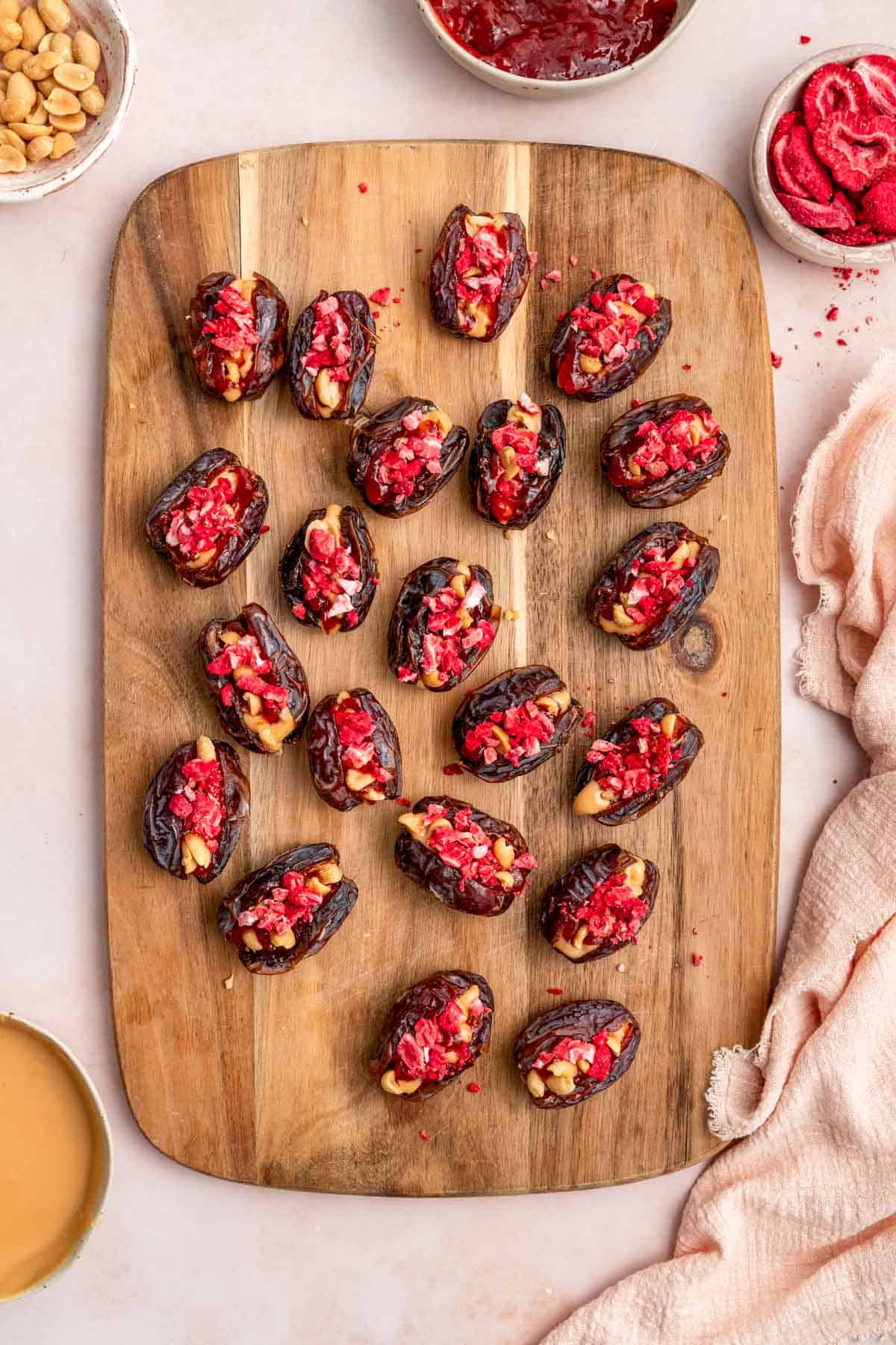 An overhead view of a wooden serving board with peanut butter and jelly stuffed dates.