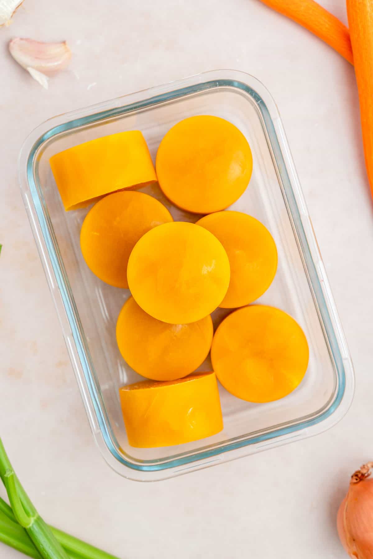 Frozen pucks of veggie packed broth in a meal prep container.