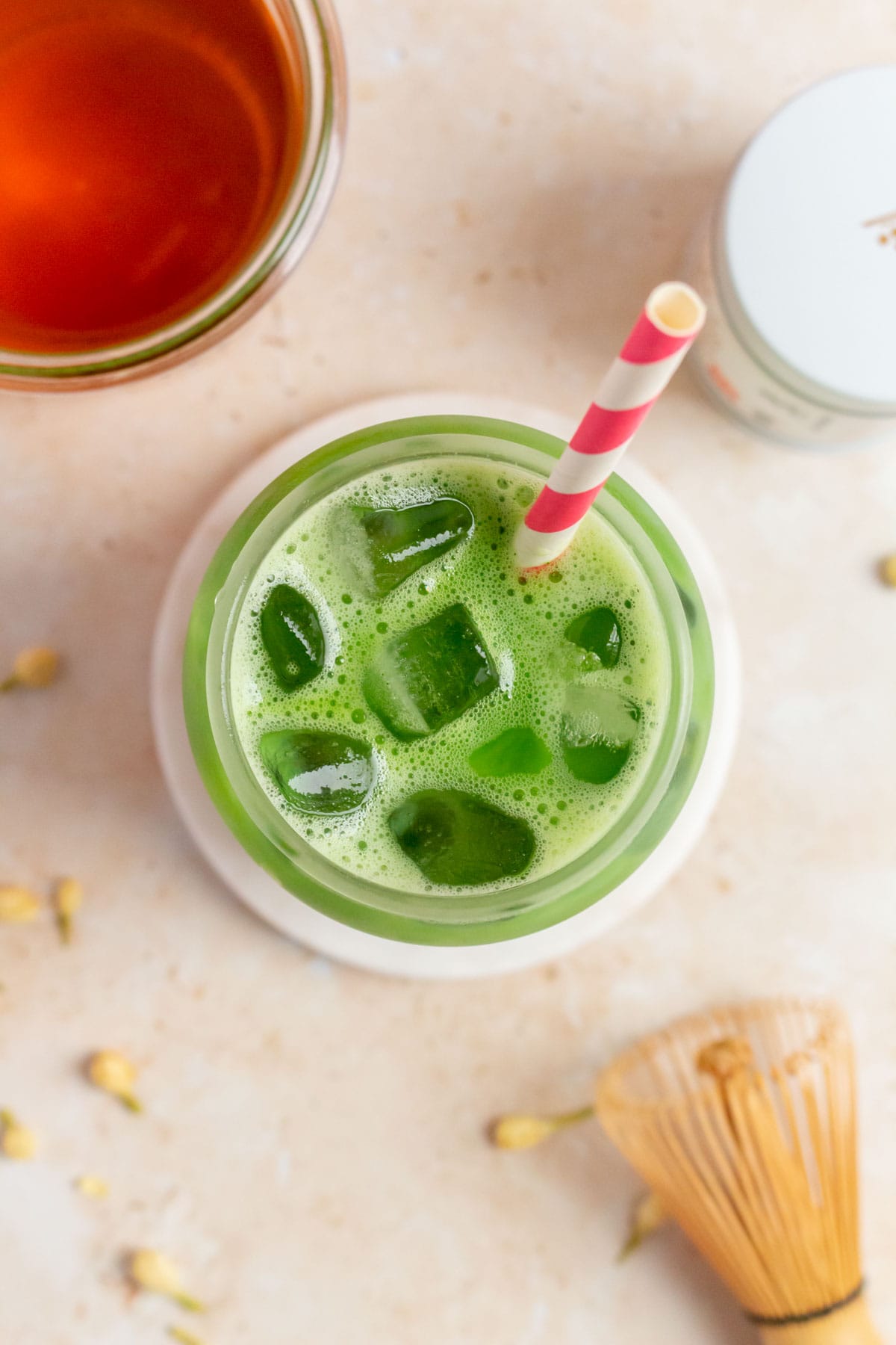 Overhead view of a glass of jasmine matcha latte with ice and a straw.