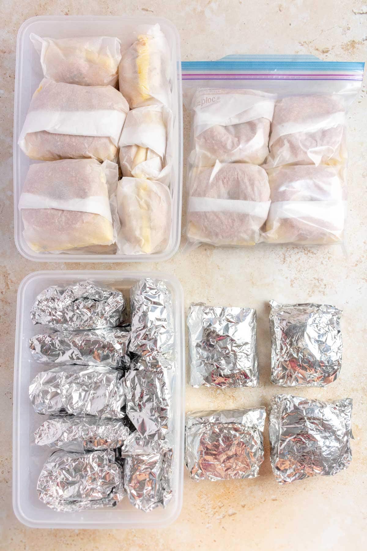 Breakfast sandwiches wrapped in parchment and foil in containers and freezer-bags.