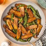 Overhead view of a skillet of baby king oyster mushroom and snap peas stir fry.