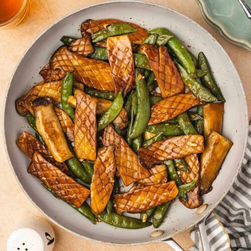 Overhead view of a skillet of baby king oyster mushroom and snap peas stir fry.