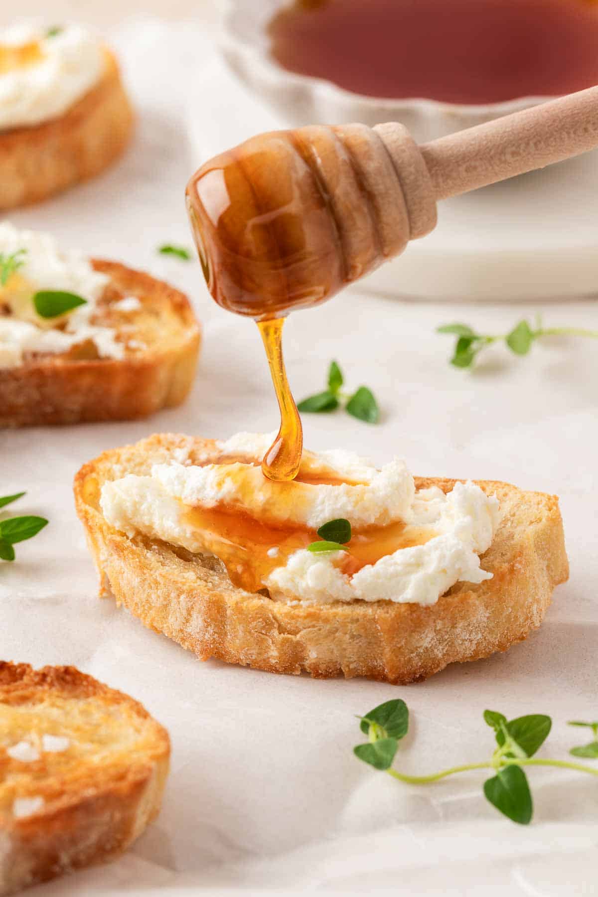 Honey drizzled on top of whipped goat cheese on a crispy crostini. Fresh thyme in scattered around.