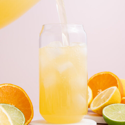 A glass with homemade lemon lime electrolyte drink being poured into it.