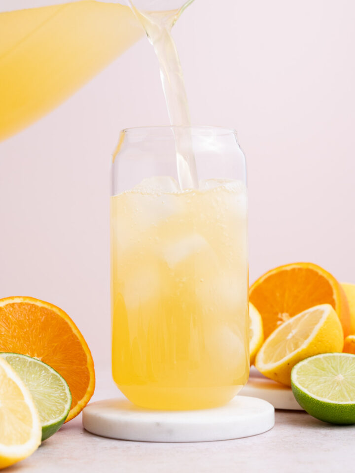 A glass with homemade lemon lime electrolyte drink being poured into it.