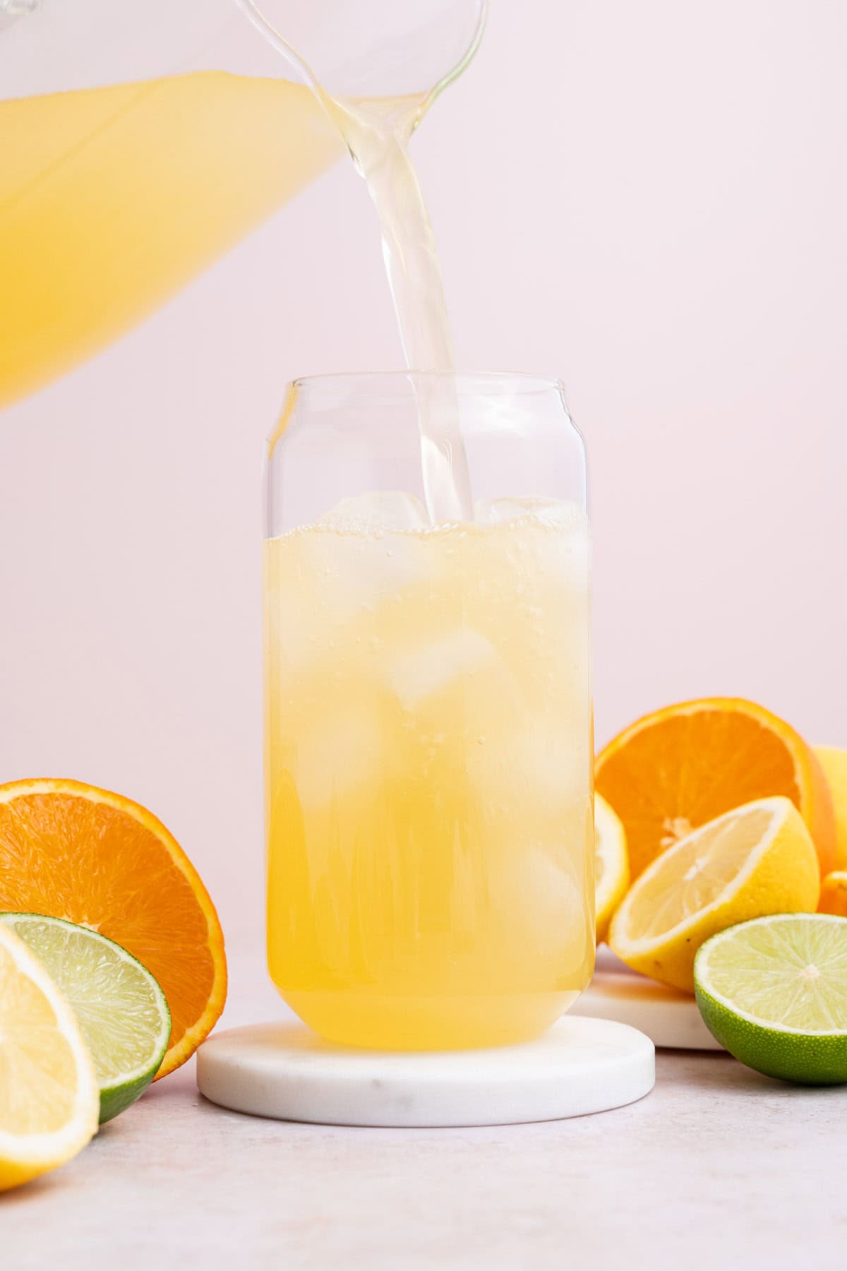 A glass with homemade lemon lime electrolyte drink being poured into it.