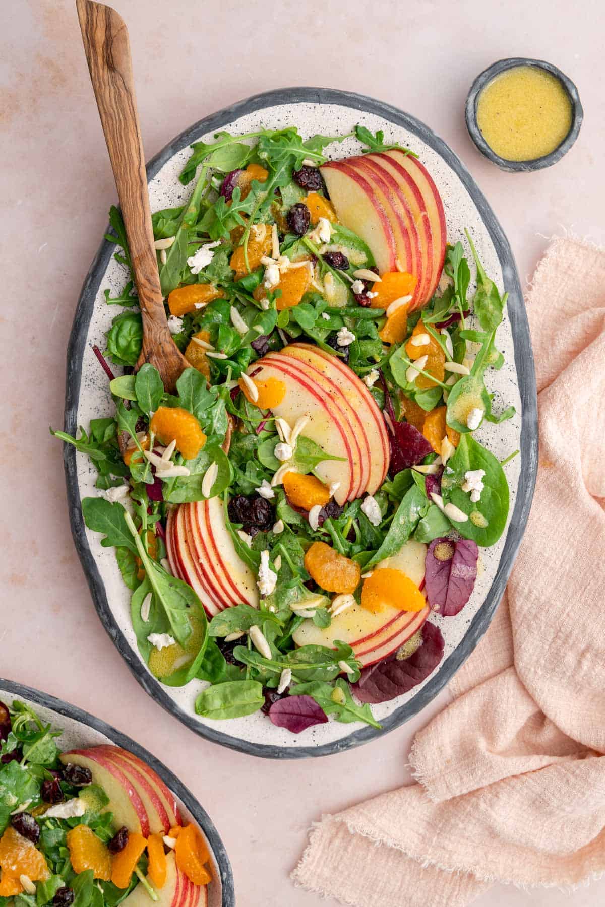 A platter of mandarin orange salad with a wooden serving spoon tucked in.