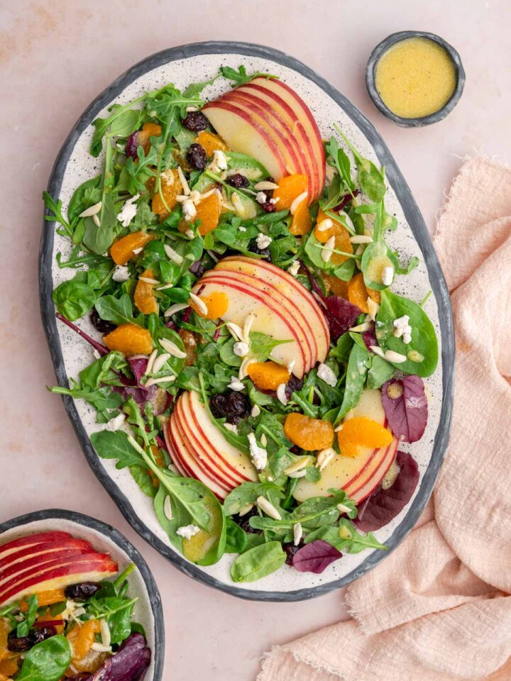 A platter of mandarin orange salad with extra dressing on the side.