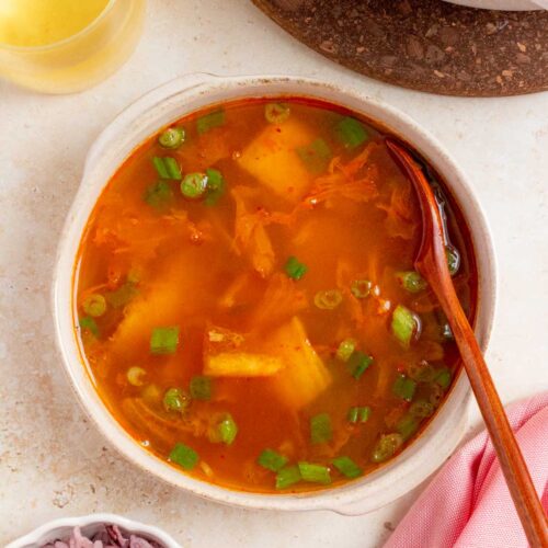 A bowl of tuna kimchi stew with a spoon.