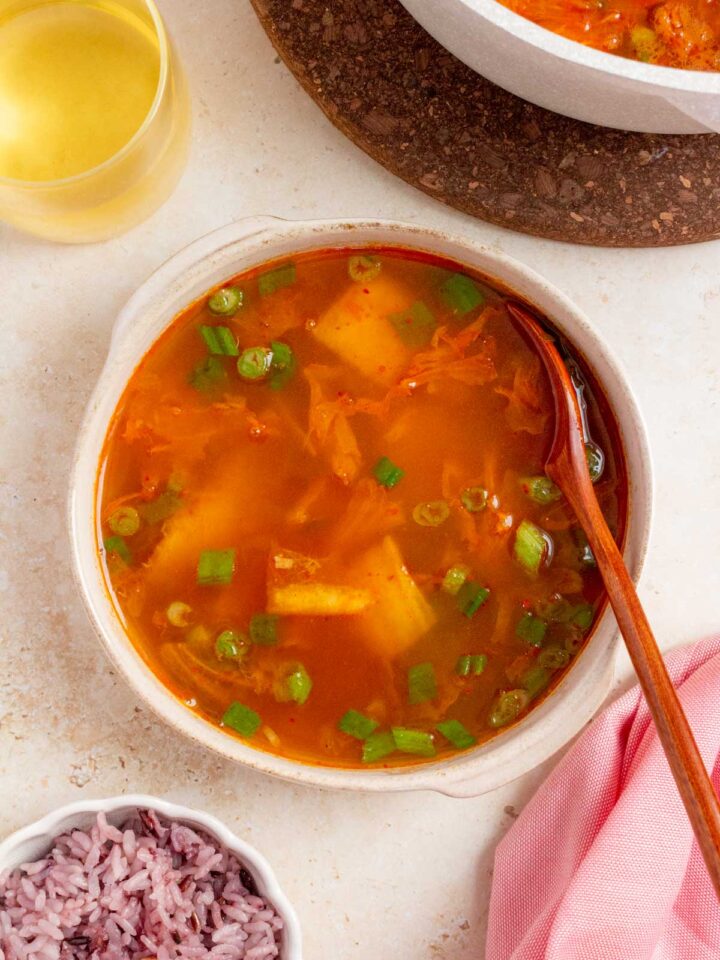 A bowl of tuna kimchi stew with a spoon.