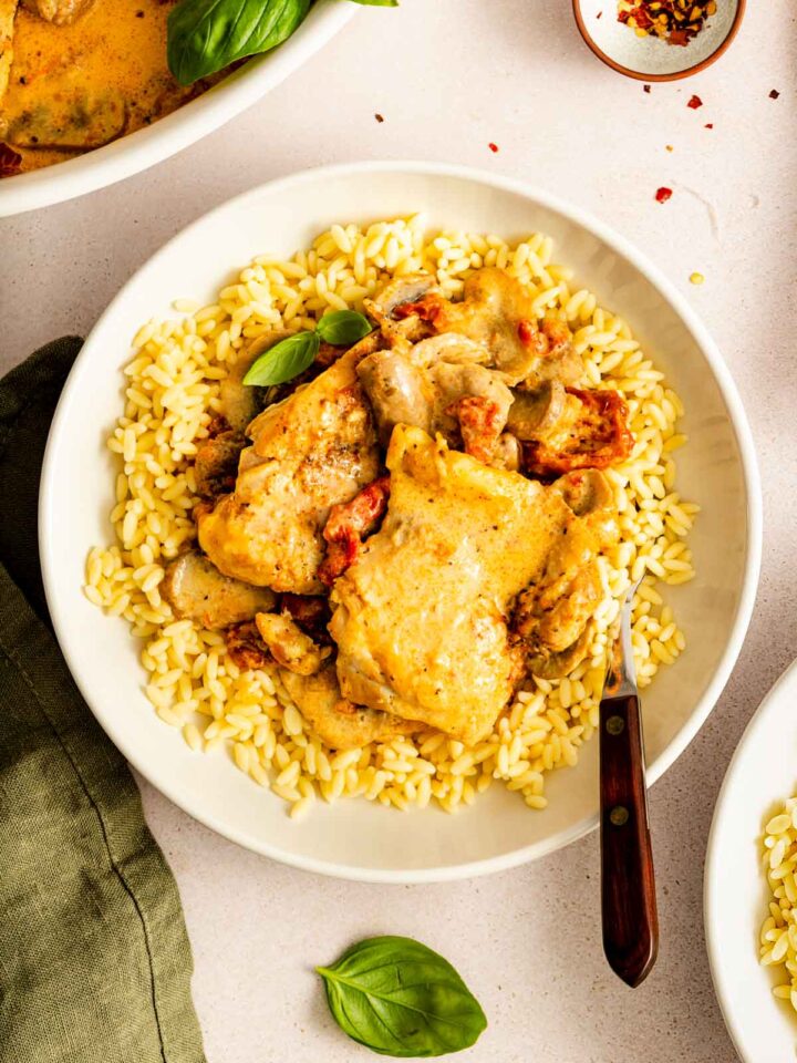 A plate of Instant Pot creamy sun-dried tomato parmesan chicken over a bed of rice.