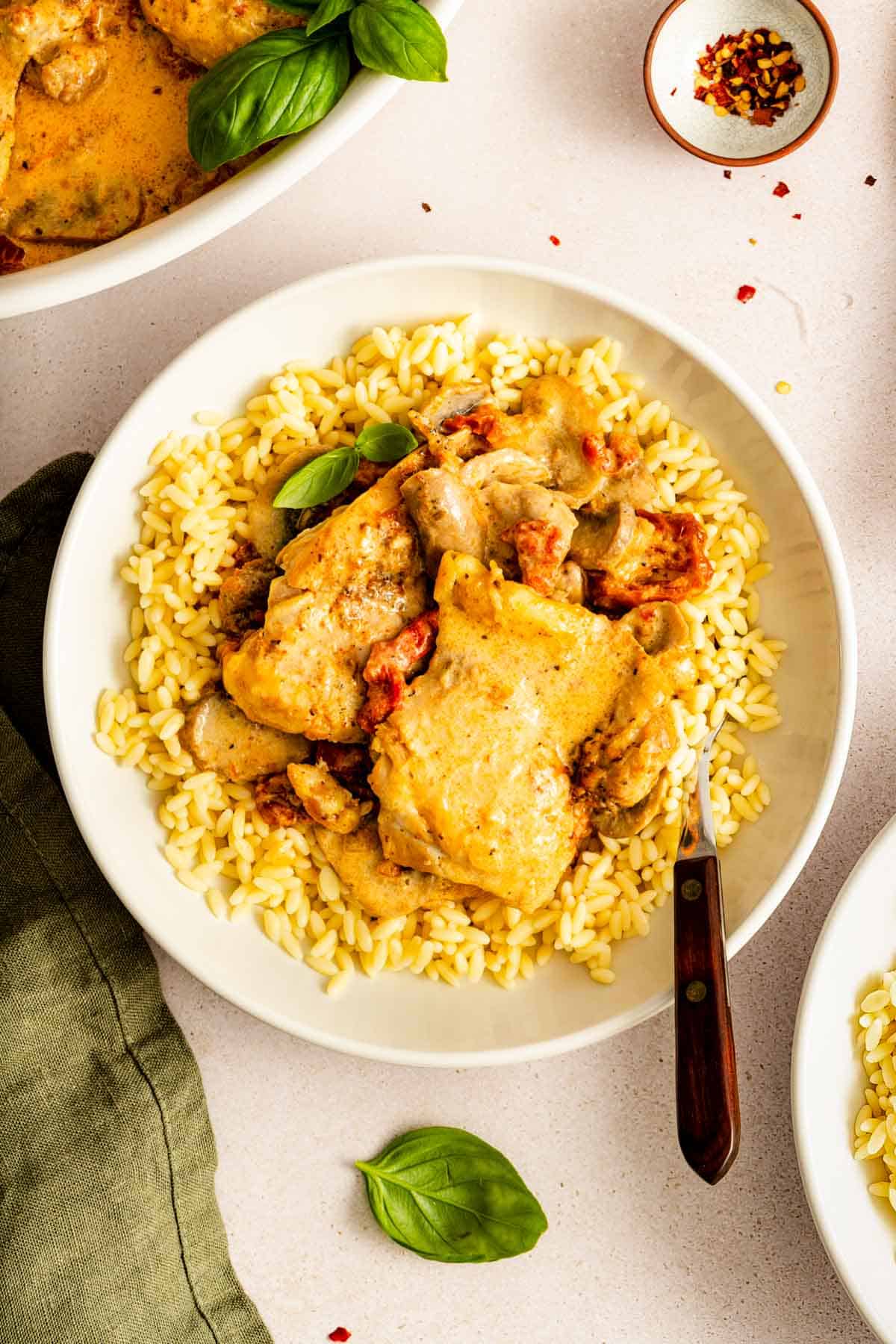 A plate of Instant Pot creamy sun-dried tomato parmesan chicken over a bed of rice.